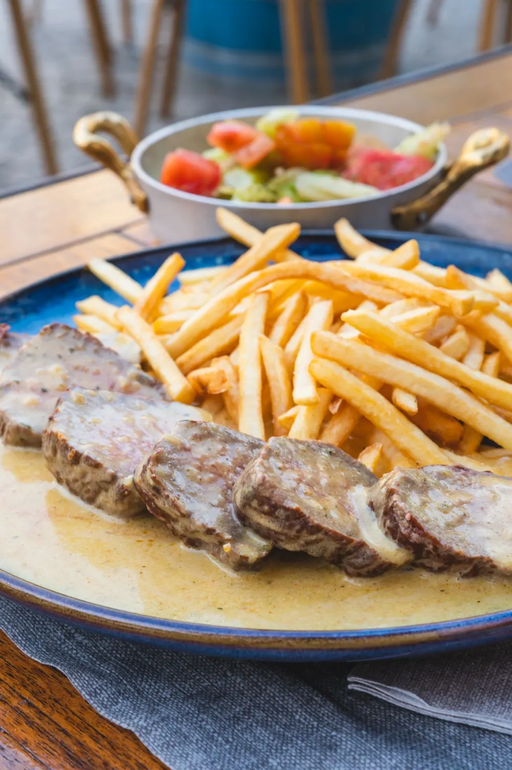 Entrecôte e patatine; dietro, l'insalata di pomodori